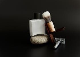 A sophisticated shaving setup featuring a brush, razor, and cream against a dark background.